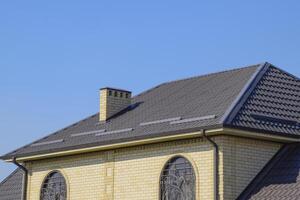 casa de amarillo ladrillo y marrón acanalado techo hecho de metal. celosías en el ventanas foto