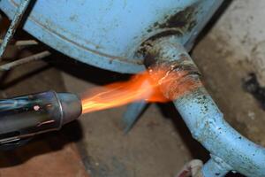 calefacción un acero tubo con un soplete. el fuego de un soplete foto