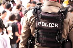 espalda ver de masculino policía oficial vestido. un bala prueba chaleco en su espalda hechizos fuera el palabra policía. Tailandia policía uniforme, proteccion y mantenimiento de paz y orden foto