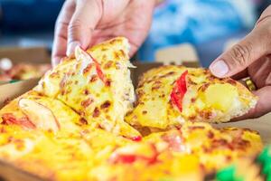 Close up of woman's hands taking a slice of cheesy tasty fresh pizza, Food delivery home concept photo