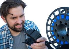 Man looking at the supports he removed from a 3D print. photo