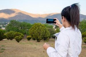 Latin woman using her cell phone in a park. photo