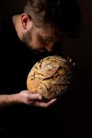 atractivo joven caucásico cocinero posando con blanco de masa fermentada un pan. foto