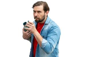 Young man drinking mate, holding the thermos in one arm. photo