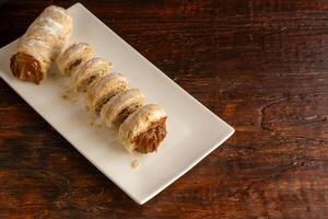 Composition of Argentine snack with cannon of dulce de leche and cup with infusion. photo