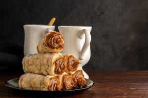 Composition of Argentine snack with cannon of dulce de leche and cup with infusion. photo