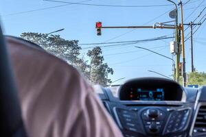 View from behind a car, of a red light, a camera and street lighting cables. photo