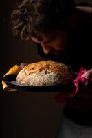 atractivo joven caucásico cocinero posando con blanco de masa fermentada un pan. foto