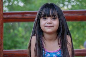 retrato de un linda argentino niña con largo cabello, quien obras de teatro en el parque. foto