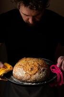 atractivo joven caucásico cocinero posando con blanco de masa fermentada un pan. foto