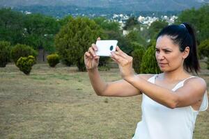 latín mujer utilizando su célula teléfono en un parque. foto