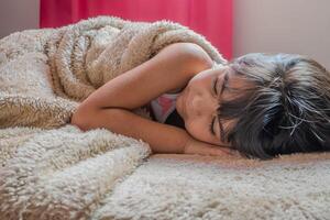 Adorable child taking a nap between the bed sheets. photo