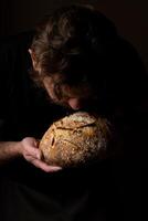 atractivo joven caucásico cocinero posando con blanco de masa fermentada un pan. foto