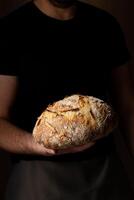 atractivo joven caucásico cocinero posando con blanco de masa fermentada un pan. foto