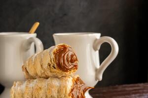 Composition of Argentine snack with cannon of dulce de leche and cup with infusion. photo