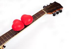 acústico guitarra cuello y rojo corazón en contra blanco antecedentes. amar, relajarse y música concepto. foto