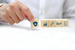 Hand holding a wooden block cube with security icon symbol. Business strategy and target of business. photo