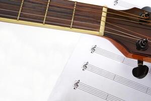 Focus the acoustic guitar neck and blur musical notes on white background. Love, music and learning concept. photo