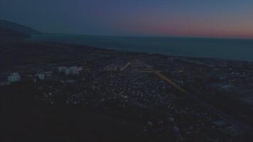 natt panorama av de stad av sochi från en fåglar öga se. klämma. panorama av sochi från de luft. hus, gator, träd, de natt himmel är synlig. i de distans du kan ser de hav. sochi, ryssland video