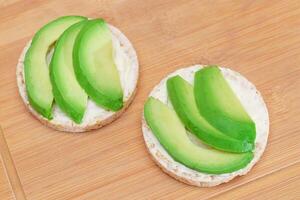 Rice Cake Sandwiches with Fresh Avocado and Cream Cheese on Bamboo Cutting Board. Easy Breakfast. Diet Food. Quick and Healthy Sandwiches. Crispbread with Tasty Filling. Healthy Dietary Snack photo