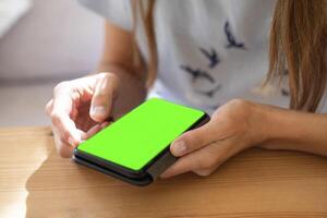 joven mujer utilizando teléfono inteligente con verde pantalla para desplazamiento noticias, fotos, en línea laboral, compras foto