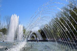 City fountain in the city of Krasnodar. People are walking by the fountain. Water splashes. photo