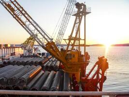 The deck lay barge. Pipes and Lifting cranes on the ship. Equipment for laying a pipeline on the seabed photo