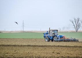 lozano y aflojar el suelo en el campo antes de siembra. el tractor arados un campo con un arado foto