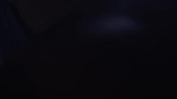 manlig boxare boxning i stansning väska med dramatisk kantig belysning i en mörk studio. hand av boxare och stansning väska över svart bakgrund stänga upp video