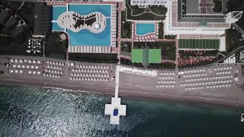 Luxury Hotel Resort pools, garden, property, shoreline and beach from above. Video. Top view aerial beach line with hotel. Top down overhead aerial view by drone video