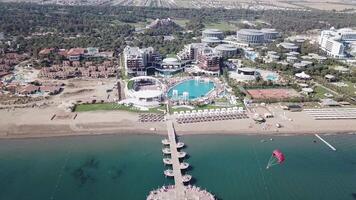 Hotel on the shore of the blue sea. Video. White sand, beautiful beach, tall palm trees. Vacation on the shore of the ocean. Aerial view video
