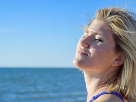 The girl relaxes by the sea under the breath of the sea breeze. Happiness by the sea. Relaxing emotions. photo