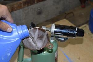 Pouring gasoline blowtorch through the funnel photo