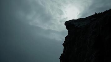 ai generado rock acantilado borde estar solo en contra un nublado cielo montaña con gris cielo foto