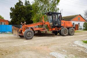 Grader on a dirt gravel road. Street repair by adding rubble. photo