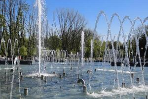 City fountain in the city of Krasnodar. People are walking by the fountain. Water splashes. photo