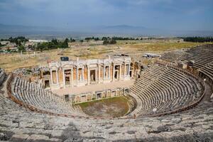 Ancient antique amphitheater in city of Hierapolis in Turkey. Steps and antique statues with columns in the amphitheater photo