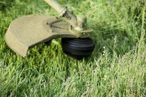 Application trimmers. Mowing green grass using a fishing line trimmer photo