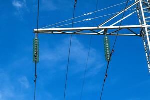 Supports high-voltage power lines against the blue sky with clouds. Electrical industry photo