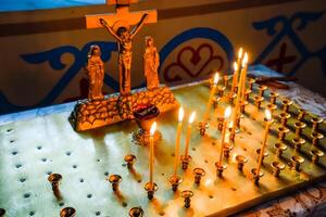 Orthodox church from the inside. Burning wax candles in front of icons and frescoes. Christian religion. photo