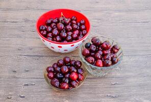 Berries of a sweet cherry on a wooden background in a plastic cup. Ripe red sweet cherry photo