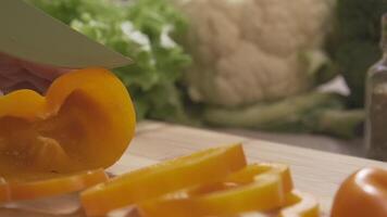 Chief cutting yellow peppers on a wooden board with a professional knife and a great skill. Scene. Close-up of chief making salad healthy food and chopping bell pepper on cutting board video