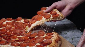 Taking slice of pizza, melted cheese dripping. Frame. Close-up Of People Hands Taking Slices Pizza black background video