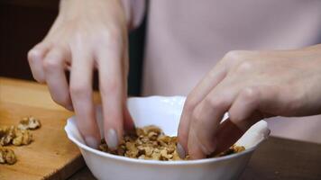 Nuts in vase. Female hands selected folder with walnut. Nuts in white plate. Girl chooses the nut video