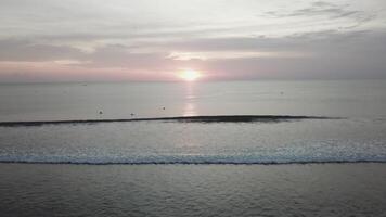 le coucher du soleil sur le plage - tranquille idyllique scène de une d'or le coucher du soleil plus de le mer, vagues lentement éclabousser sur le sable. vidéo. vagues s'écraser doucement sur silencieux sablonneux plage video
