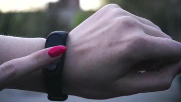 Young woman using wearable fitness tracker. The smart band with display touchpad and heart rate monitor. Entertainment and technology concept. Close-up shot of woman hand with smart watches video