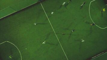 Aerial football match play. Clip. Aerial shot Two teams playing ball in football outdoors, top view. Football game outdoors, green field with markings, players running around with a ball video