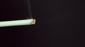 Close-up of a burning cigarette. Smoking a cigarette against a black background. Decaying cigarette close-up on a black background video