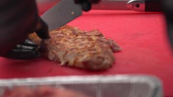 Koch im schwarz Handschuhe schneidet saftig Fleisch Steak auf das Holz Tafel mit das Messer, Nahansicht. lecker, saftig, frisch gekocht Fleisch Steaks Koch schneidet auf das Schneiden Tafel. Saft von das Steaks Überreste auf das video