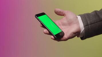 il mano di un' uomo d'affari chi mantiene un' smartphone. scorta. manica giacca e camicia parti. verde schermo. clic su il schermo di il mobile Telefono video